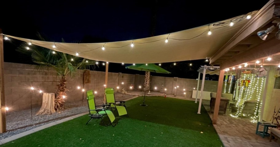 backyard with canopy and chairs and string lights around the fence and canopy