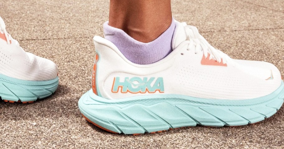 woman wearing a pair of white hoka running shoes