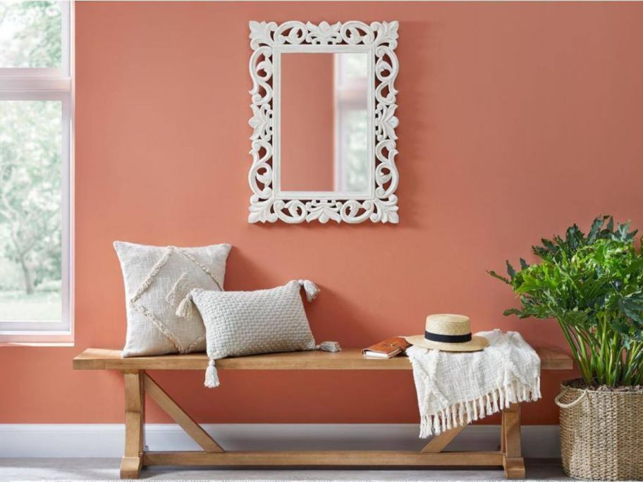 Home Decorators Collection White Wood Framed Mirror hanging on a wall over a bench with decorative throw pillows on it