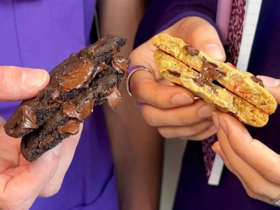 two hands holding Insomnia Cookies that are broken in half