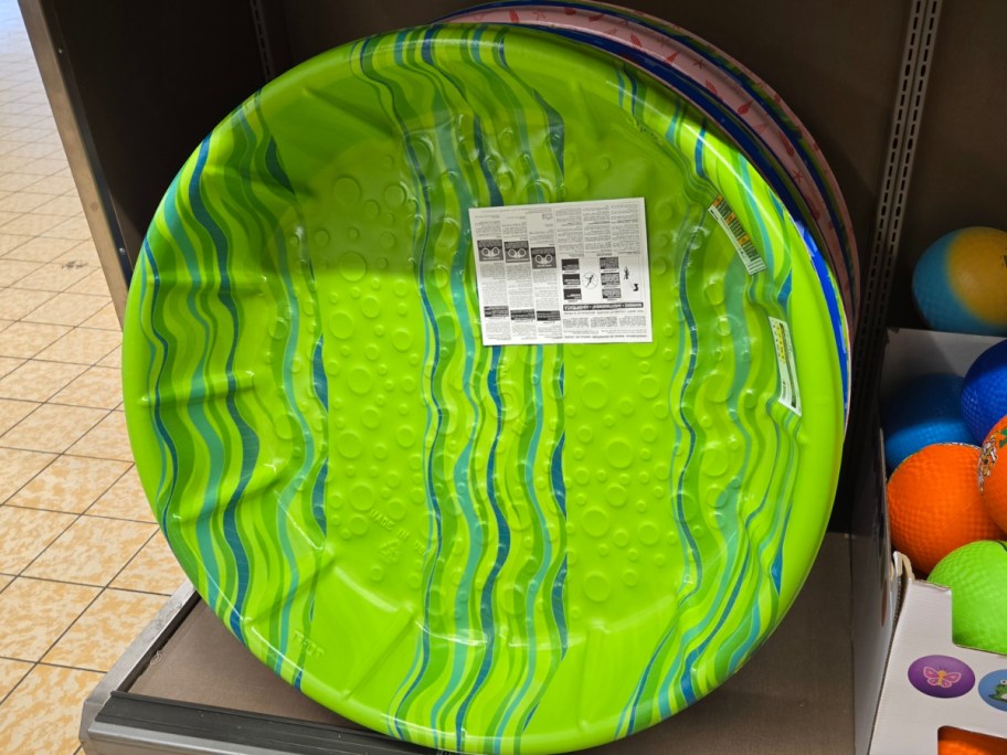 round ALDI green kiddie pool stacked on a wall with other colorful options behind it
