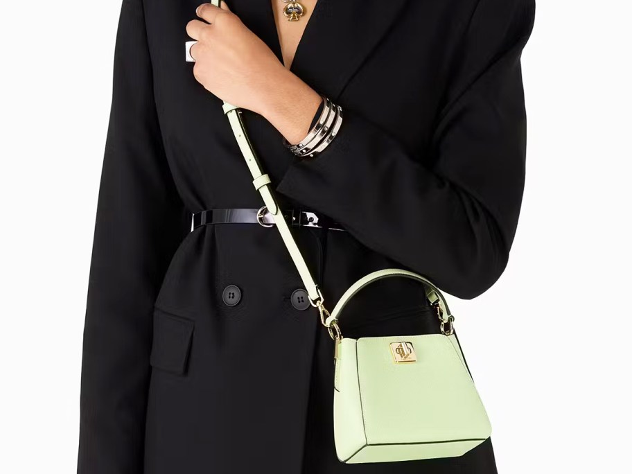 woman in a black jacket with a small green crossbody bag