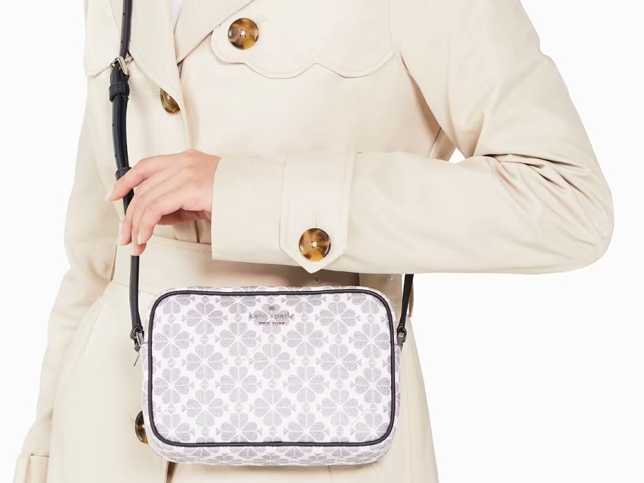 woman in a white coat with a navy floral print crossbody