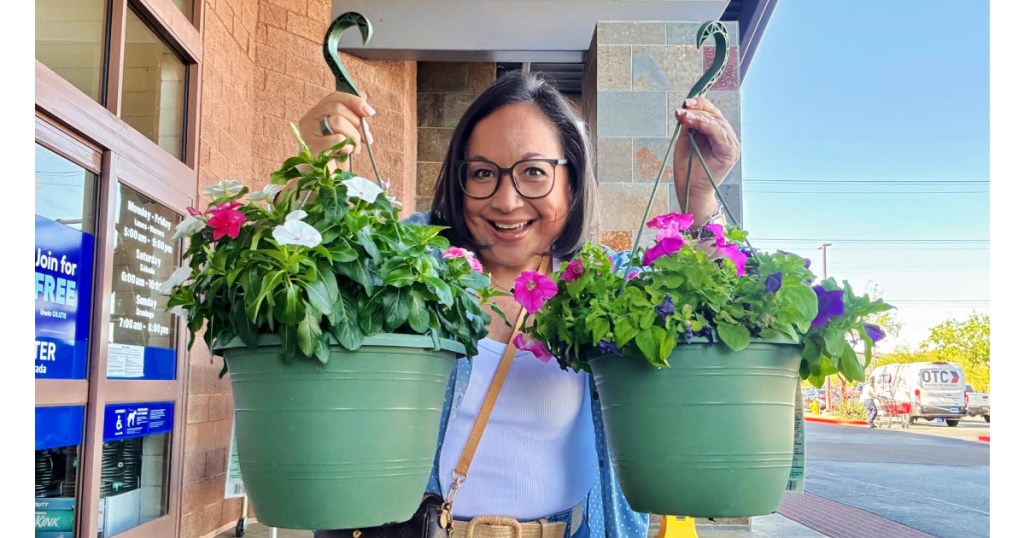 Woman holding up two flower baskets at Lowe's store