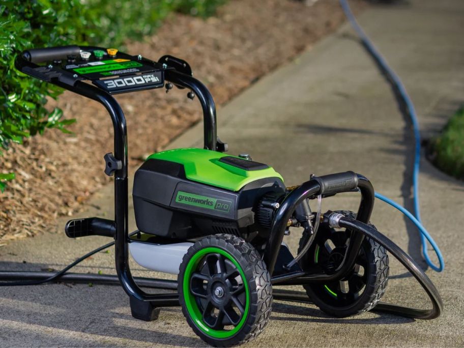 A Greenworks Pro 3000-PSI 2.0-GPM Cold Water Electric Pressure Washer on a sidewalk
