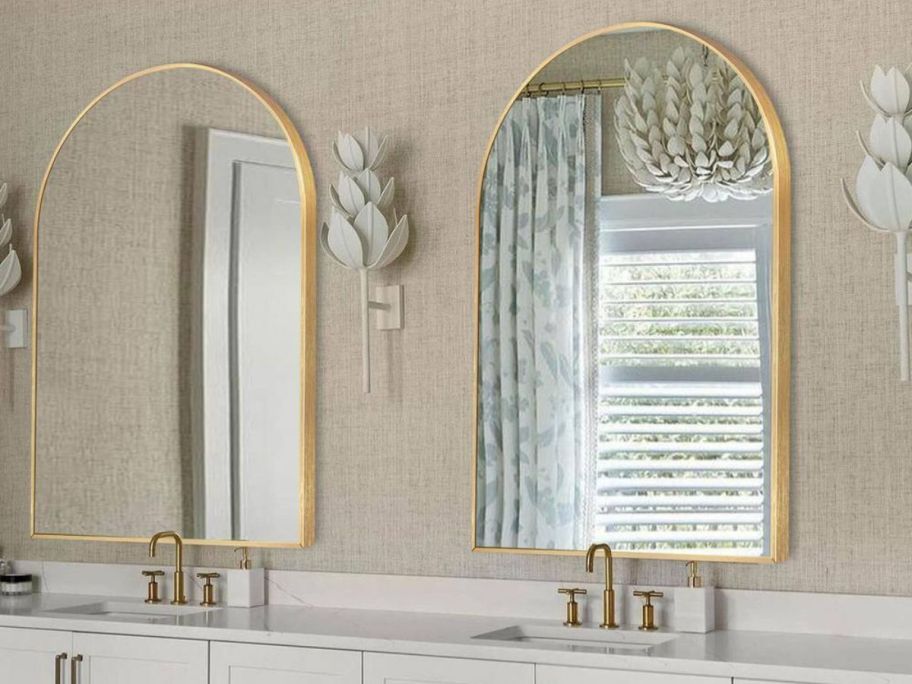 A bathroom with 2 large gold arched mirrors