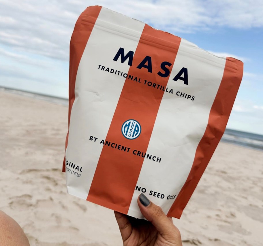 hand holding a bag of masa chips on beach