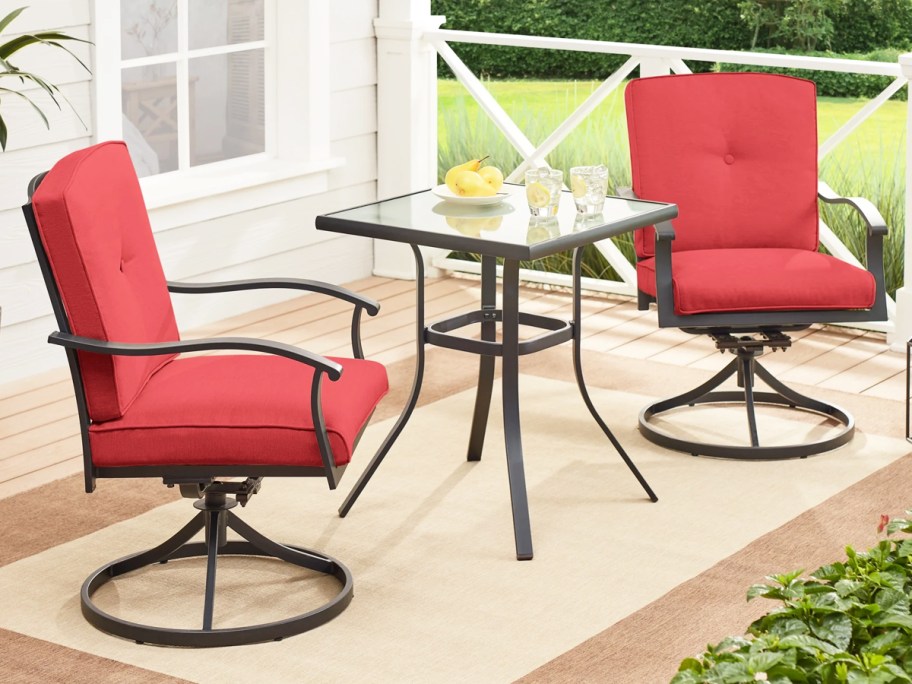 two patio chairs with red cushions and matching table