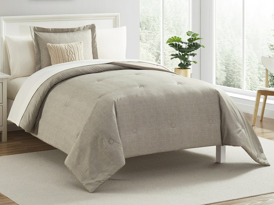 brown comforter and pillow sham on a bed with white sheets