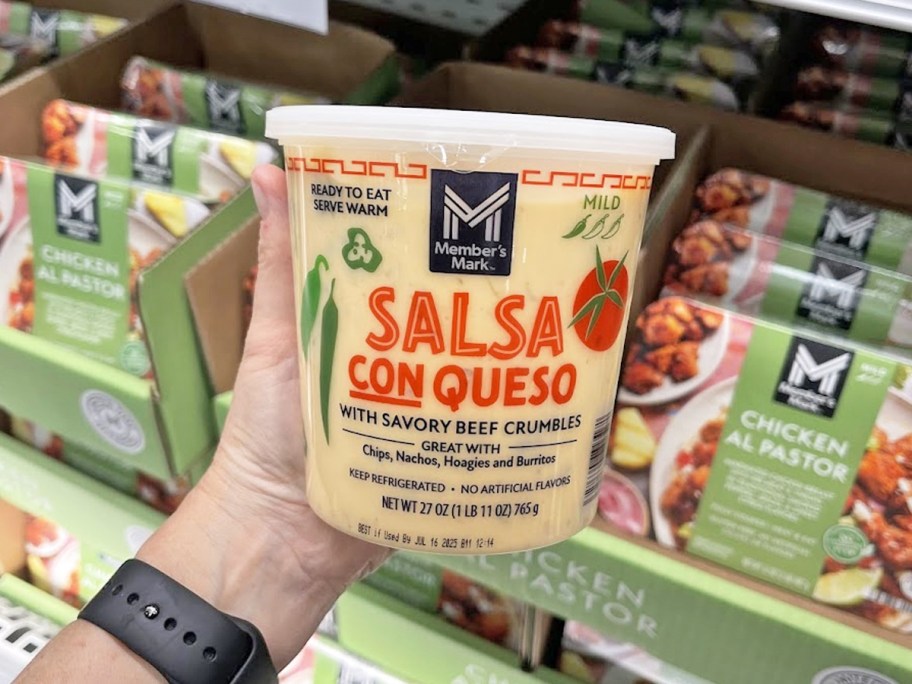 hand holding a container of Member's Mark Salsa Con Queso