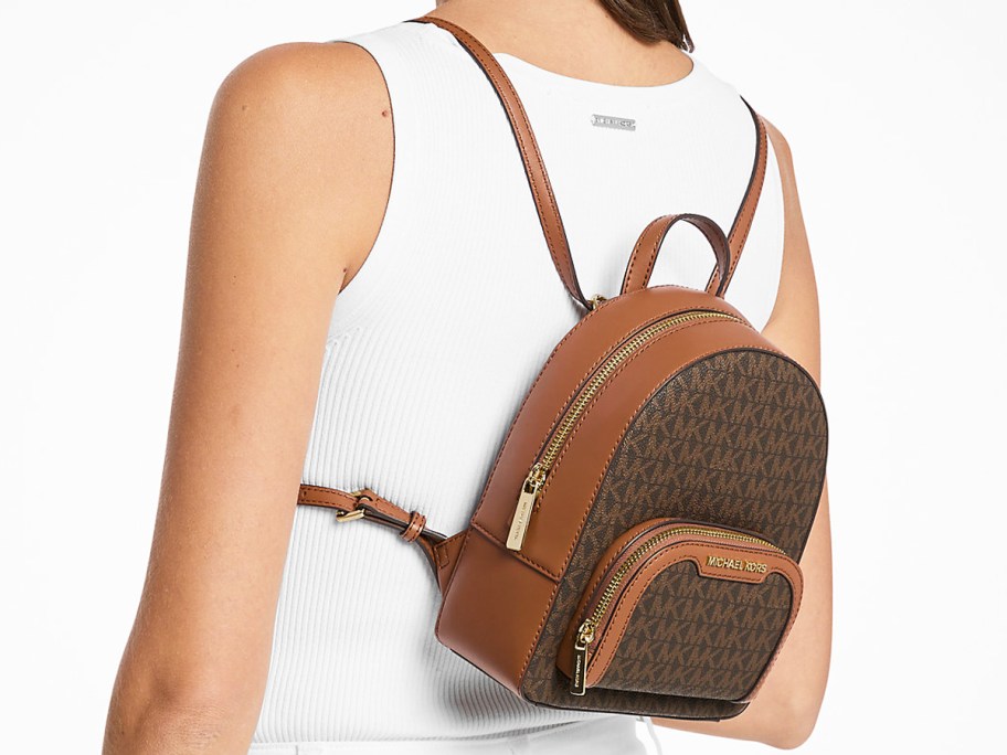 woman in a white tank top with a brown mini backpack