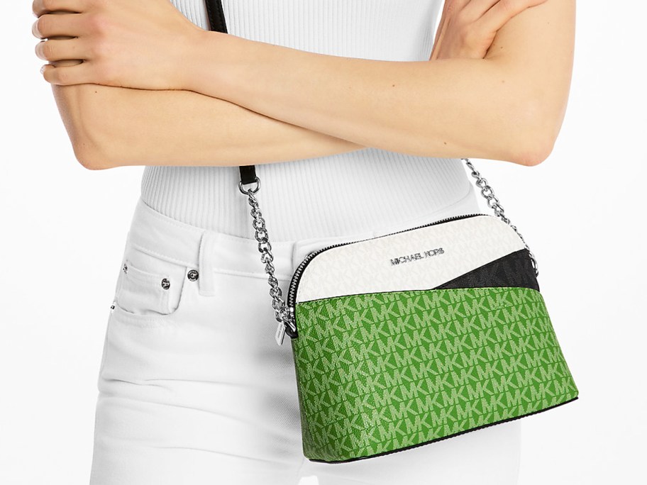 woman in a white outfit with a green, white, and black crossbody bag