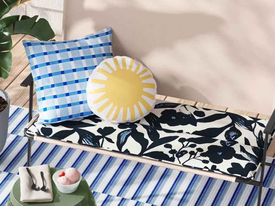 outdoor bench seat with black and white cushion and blue and yellow throw pillows
