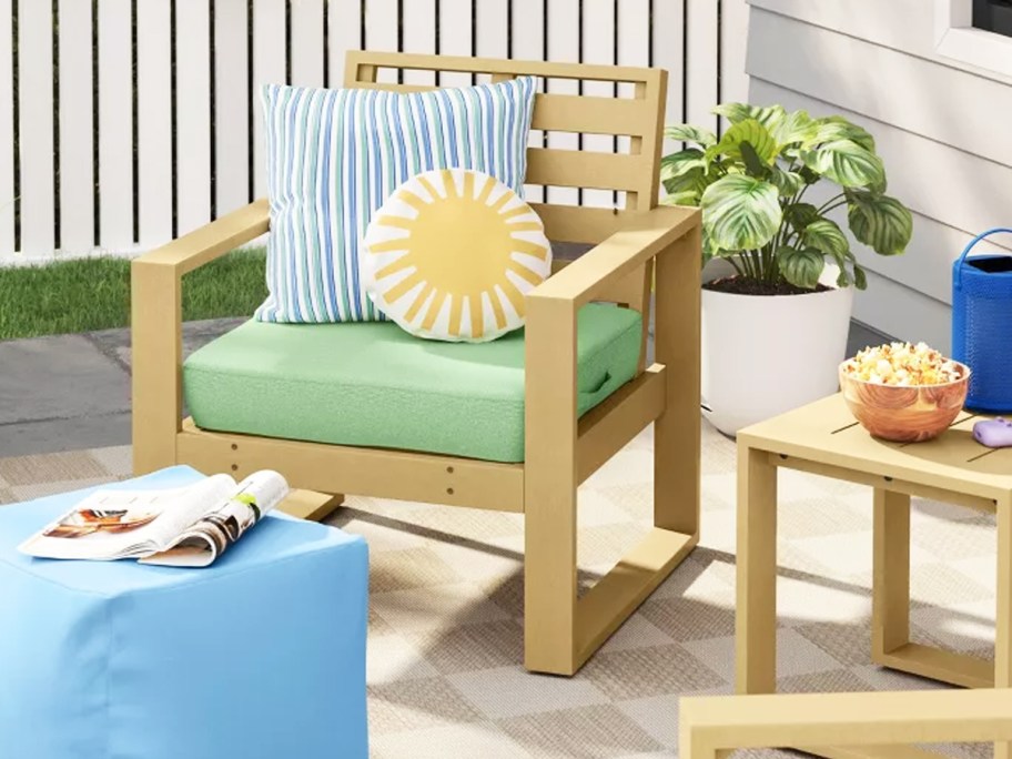 wood patio chair with green cushions and blue and yellow throw pillows