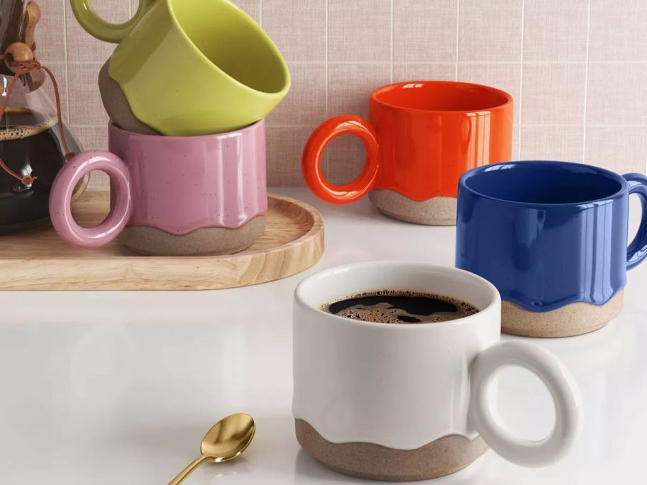 5 drippy glazed mugs on a counter
