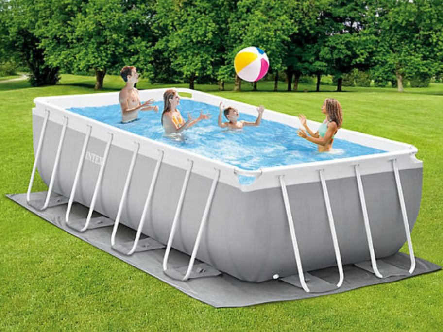 A family of 4 playing with a beach ball in an Intex Prism Frame Rectangular Above Ground Pool 