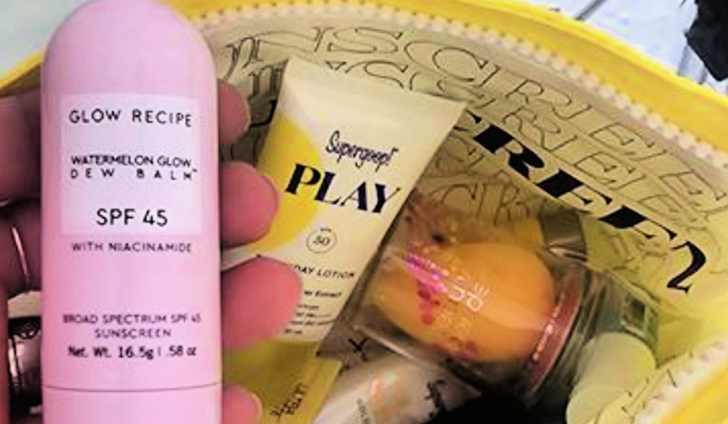 Person holding up sunscreen and other items from the Sephora sun safety kit