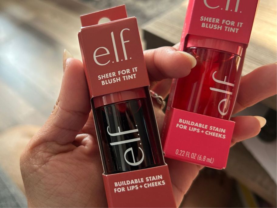 A woman holding 2 blush tint bottles in boxes