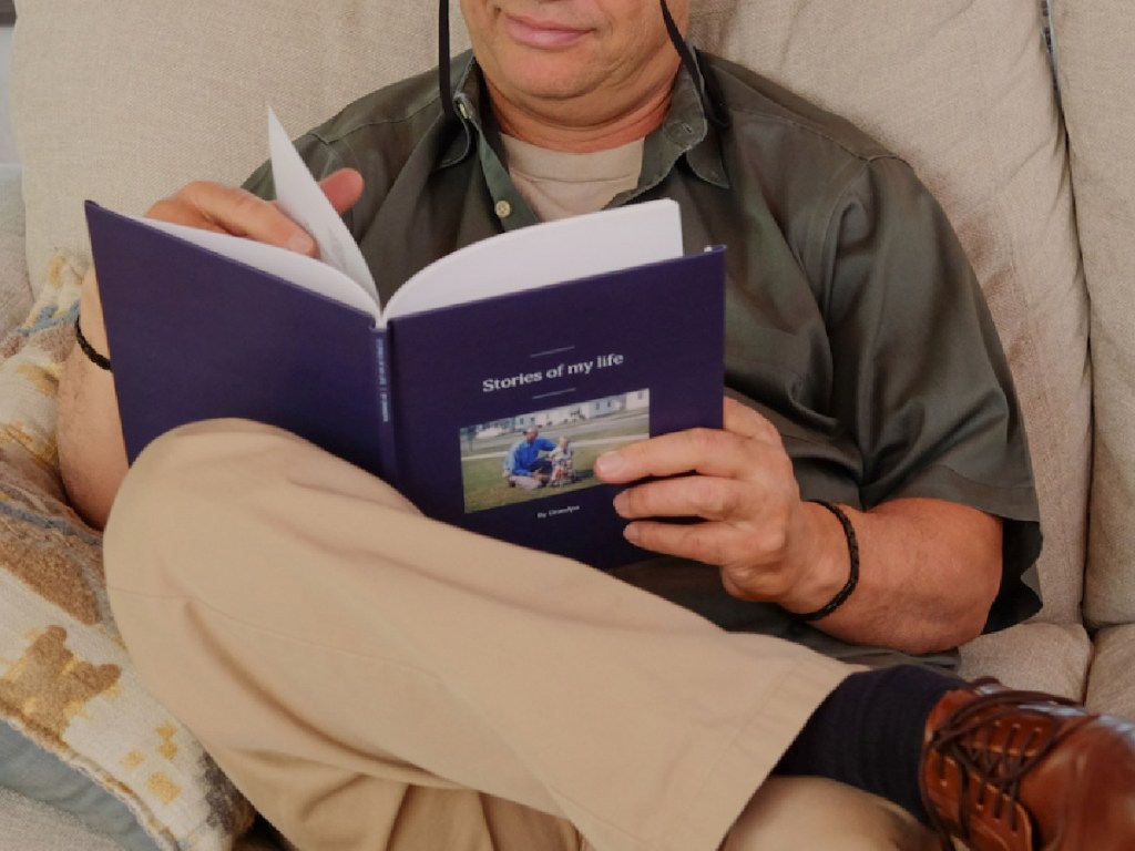 Man sitting on couch reading stories of my life book