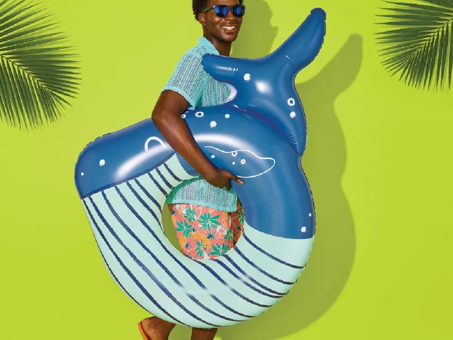 person holding whale swim float in front of a green wallpaper