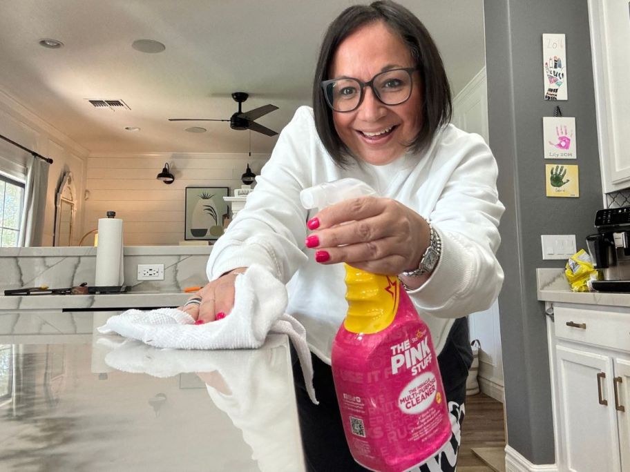 woman spraying a bottle of The Pink Stuff Miracle Multi-Purpose Cleaner Spray