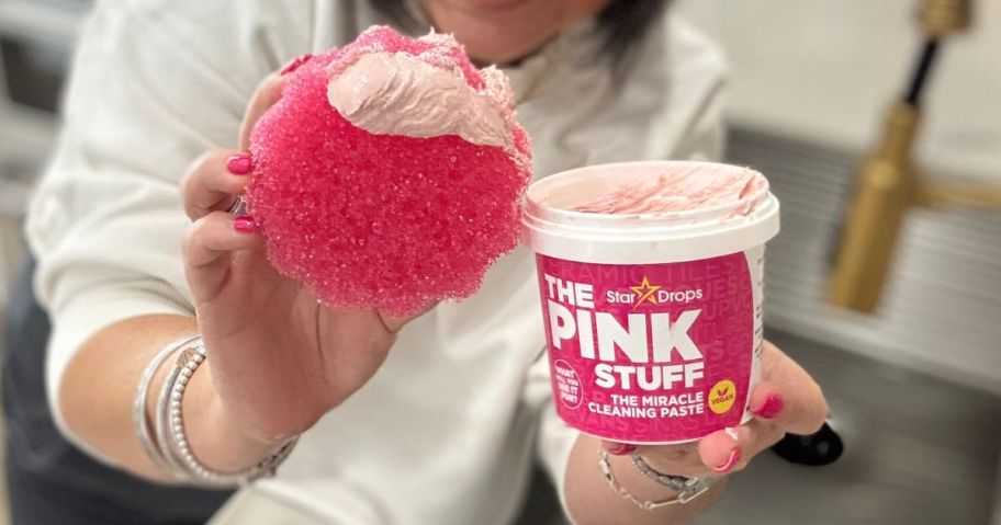 Woman holding a small tub of The Pink Stuff Cleaner and a Sponge