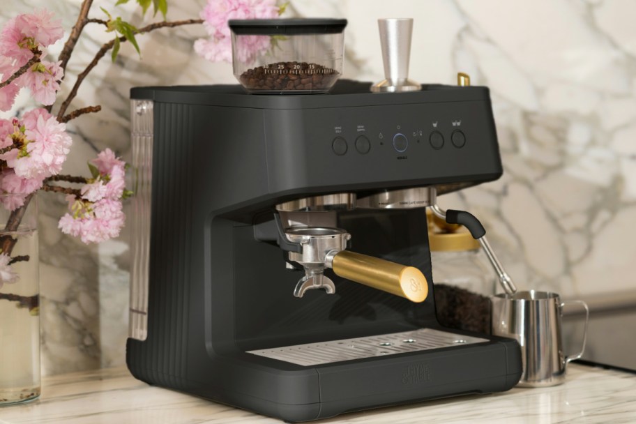 Espresso grade coffee maker next to flowers displayed on a kitchen counter