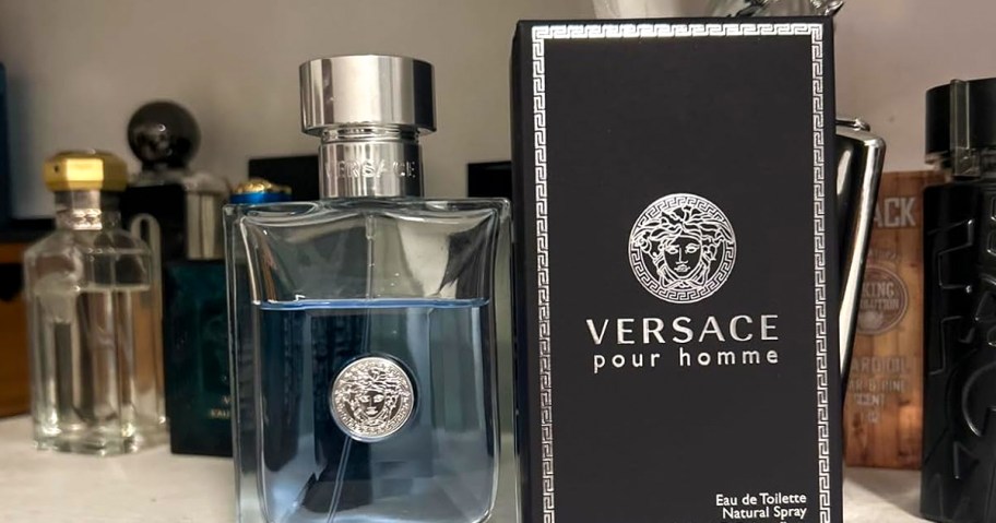 Versace Pour Homme Eau de Toilette bottle and box displayed on a shelf with other men’s fragrances in the background.