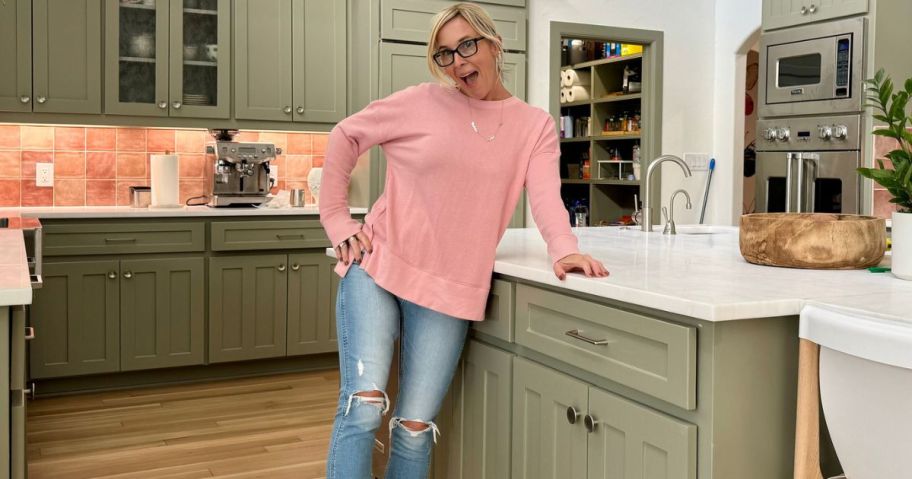 Woman standing in a kitchen wearing ripped jeans and a Time & Tru Sweatshirt from Walmart