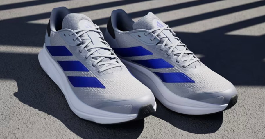 pair of grey and blue adidas running shoes on cement