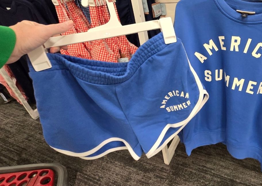 a womans hand holding out a pair of blue fleece running shorts with white trim