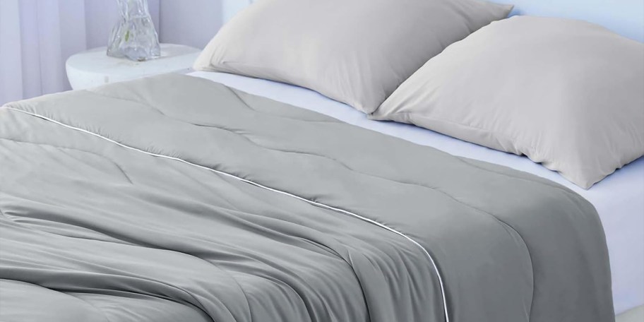 gray cooling comfoter on bed with pillows 
