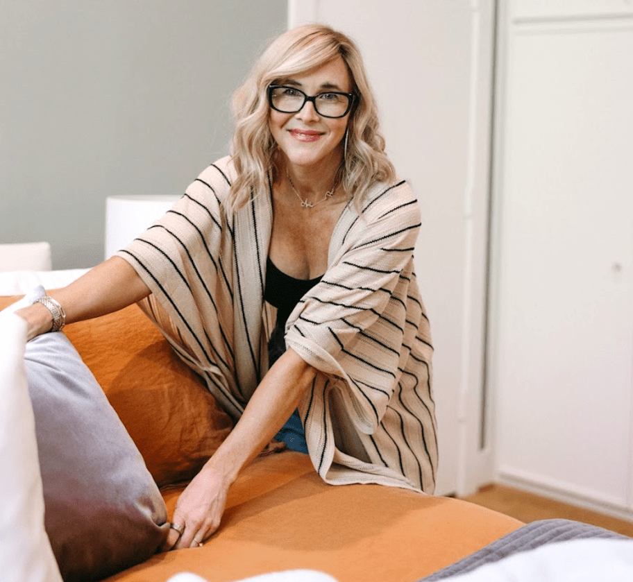 woman fluffing pillow on bed