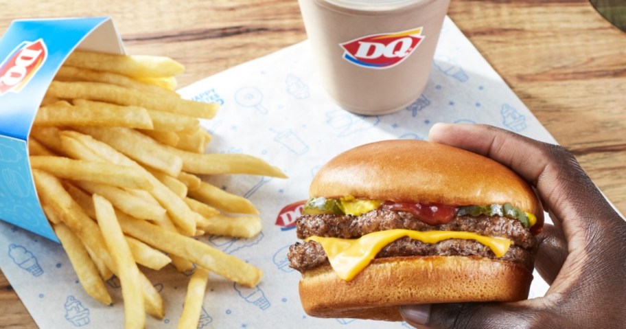 holding a Dairy Queen burger next to fries and a shake