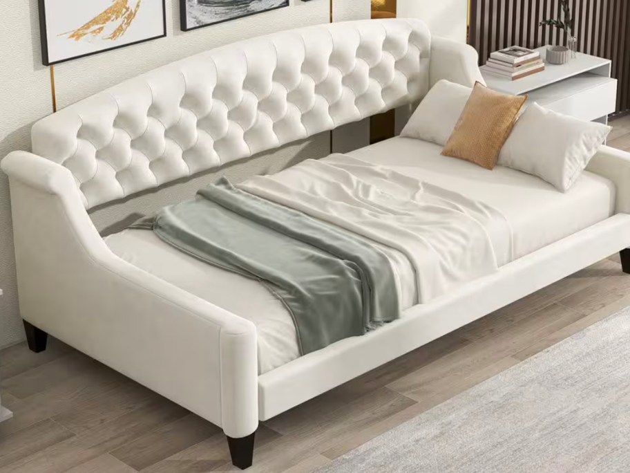 beige daybed with green blanket 