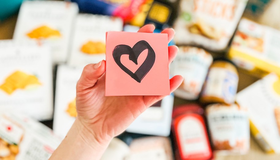 hand holding pink post it with heart