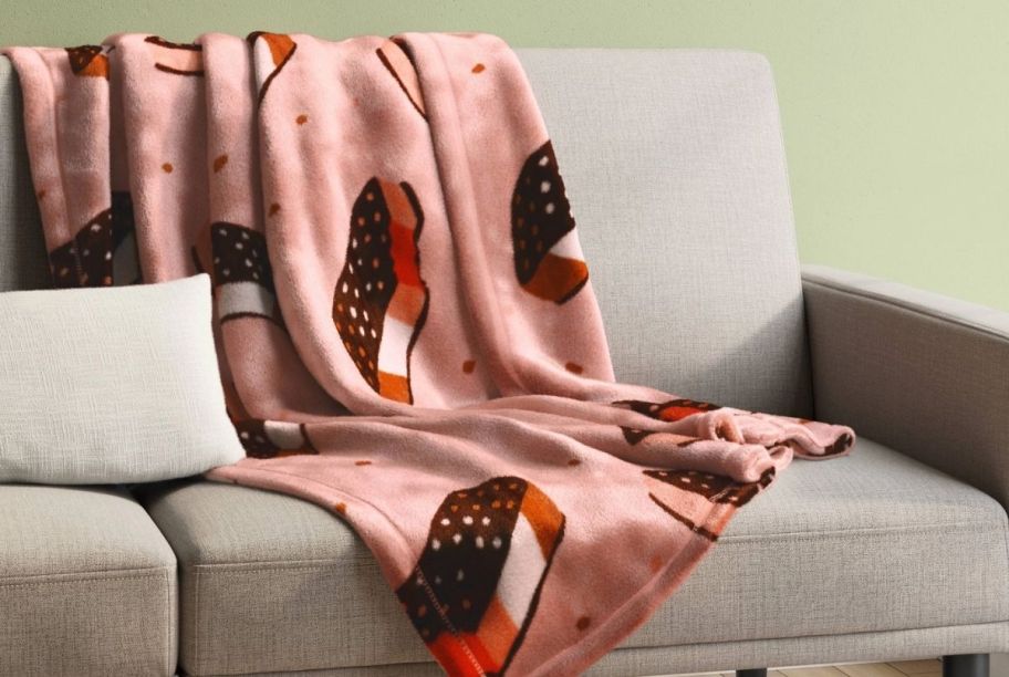 a pink throw blanket with ice cream sandwich graphics printed all over. the throw is shown draped over a sofa