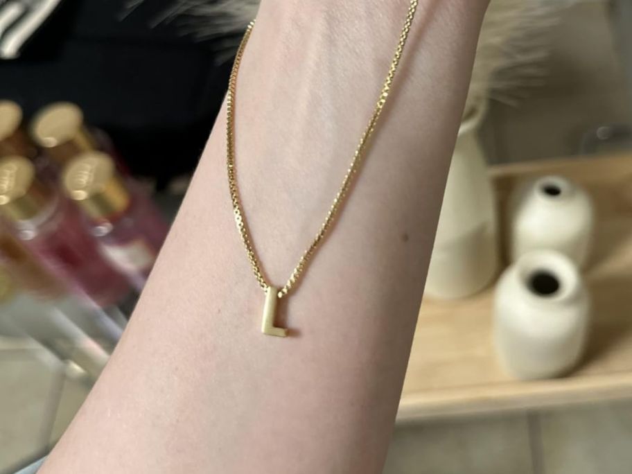 initial necklace with an L on it hanging on a woman's arm