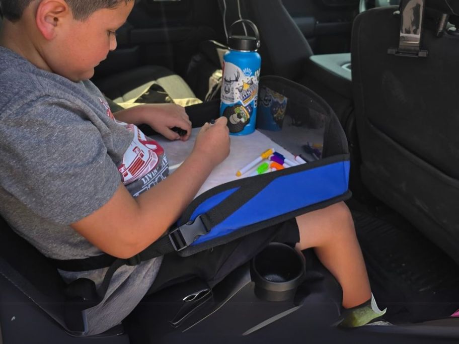 kid drawing on dry erase board on kids travel tray in car