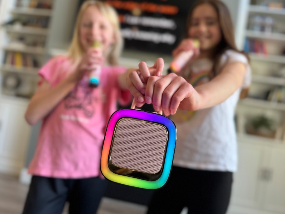 two girls holding microphones and a karaoke machine
