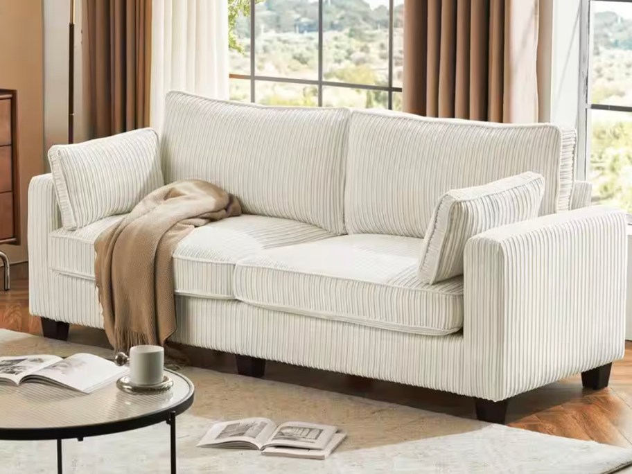 beige loveseat in living room with brown blanket 
