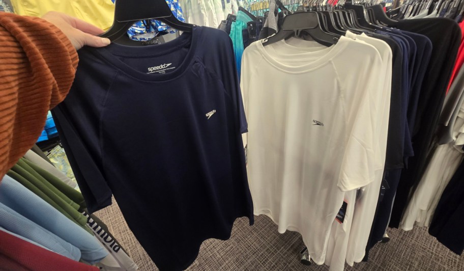 navy and white rash guards on hangers in store
