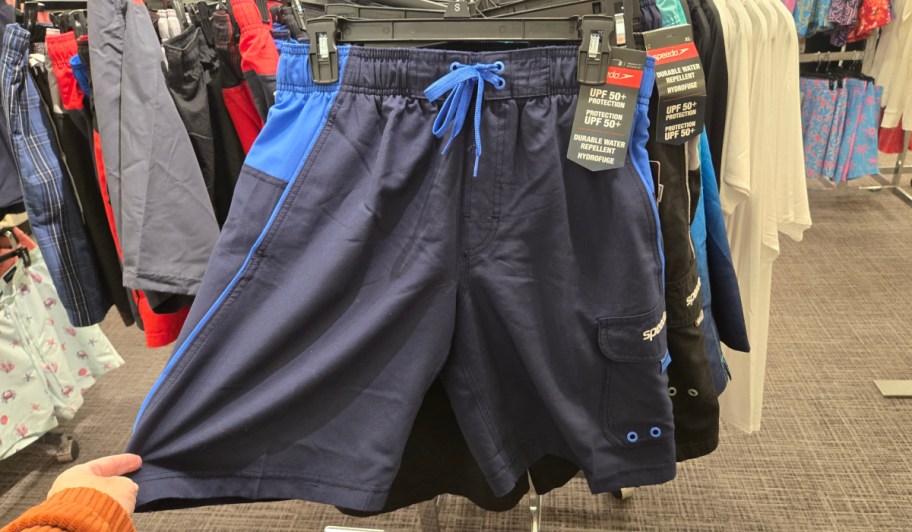 hand pulling navy blue swim trunks off hanger