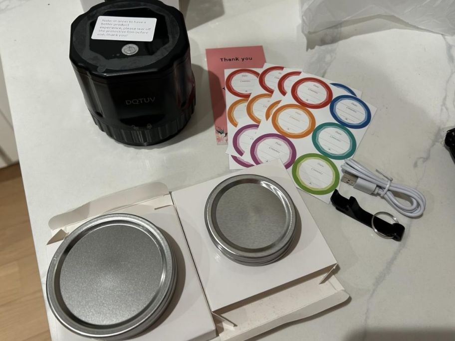 a mason jar sealer on a kitchne counter shown with accessory kit that includes lids and labels