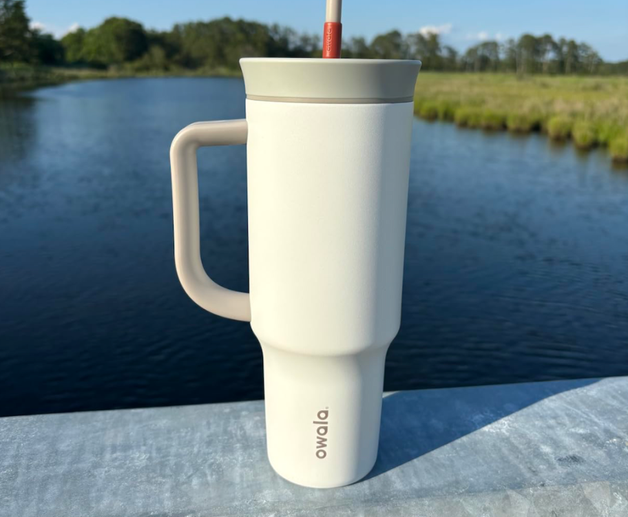 white owala tumbler with gray lid sitting in front of water
