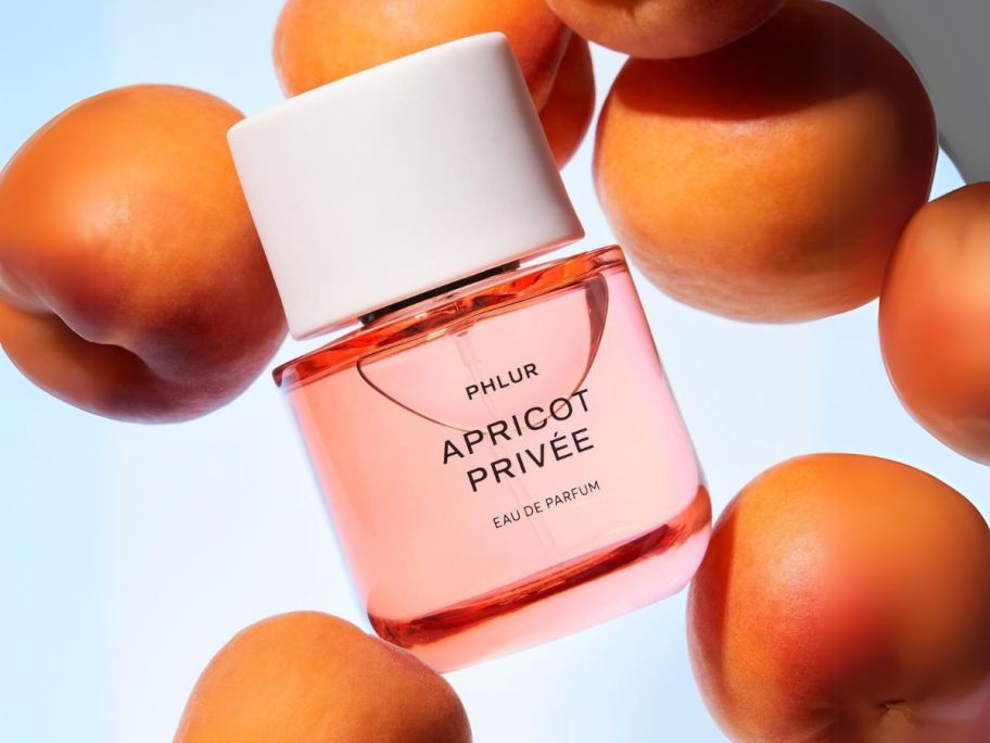 PHLUR Apricot Privee Eau de Parfum bottle amongst apricots