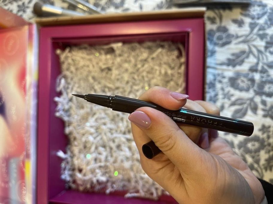 person holding eye liner in hand