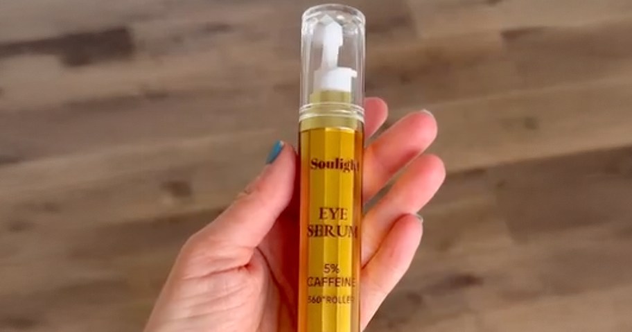 person holding gold tube of caffeine eye serum