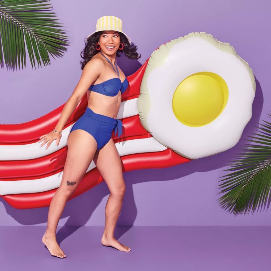 woman in a swimsuit with a bacon and egg pool float