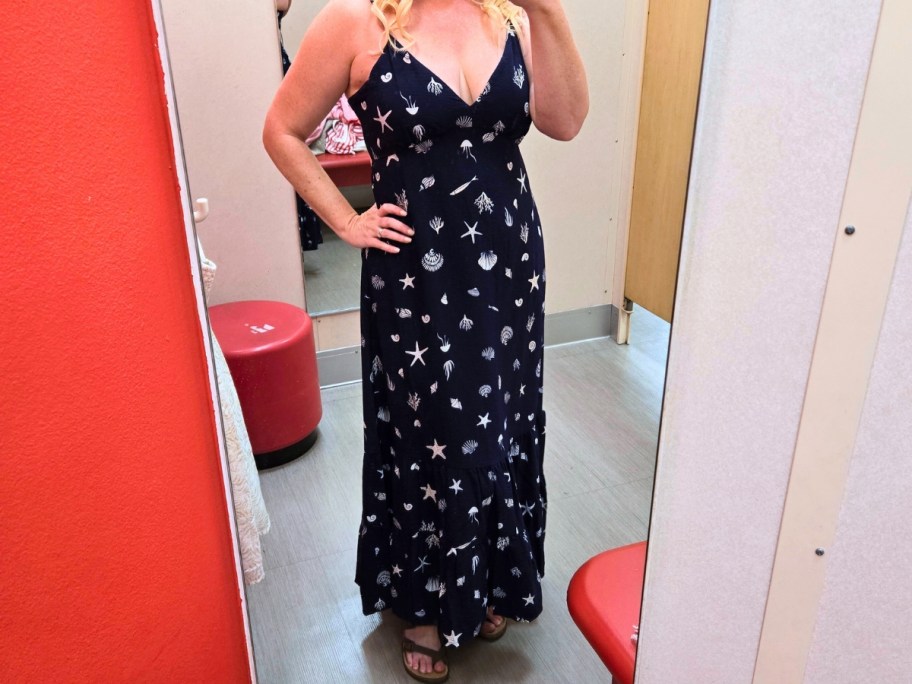 woman taking a selfie in a dressing room mirror wearing blue floral spaghetti strap dress